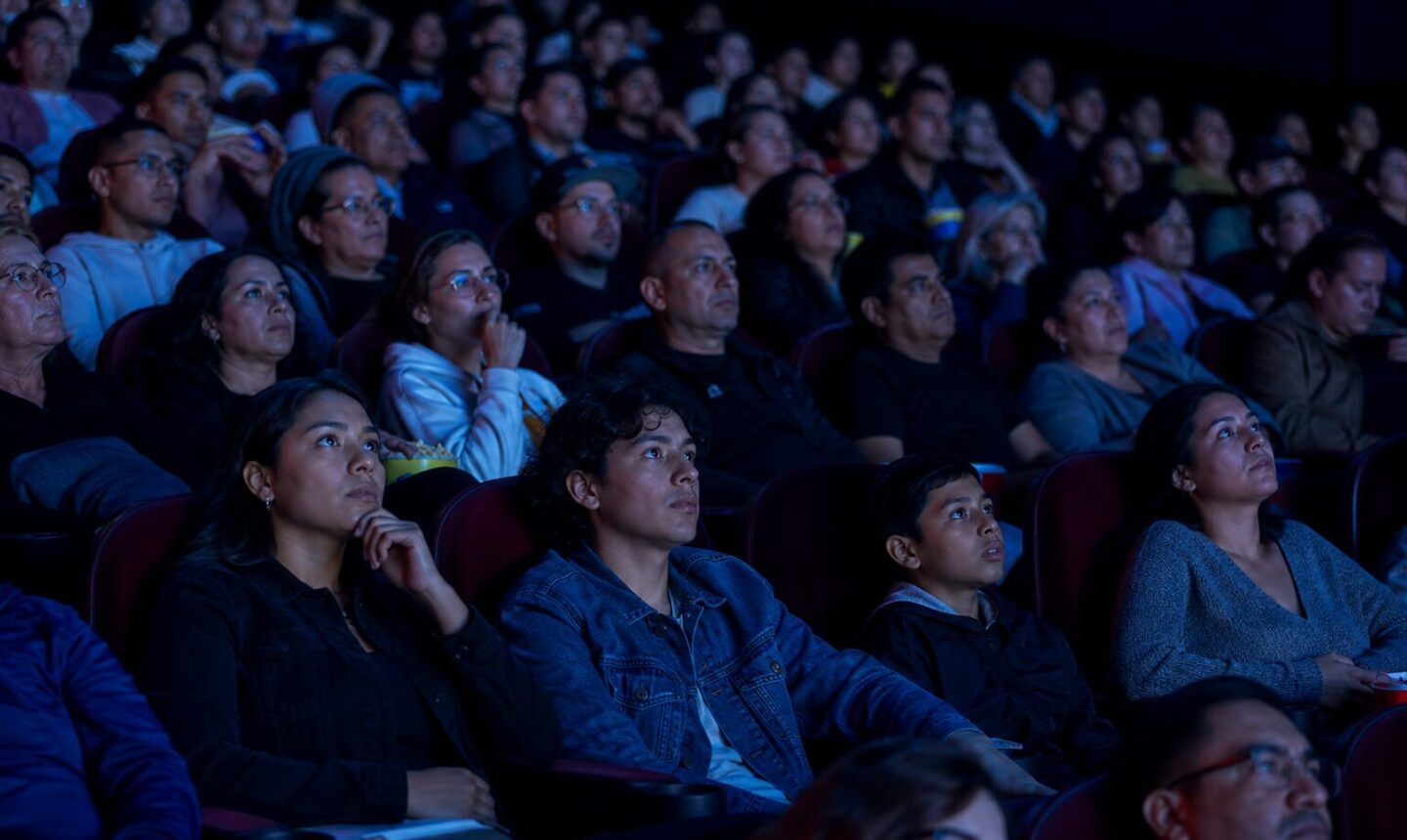 Espectadores observan una película de superhéroes en una sala de cine llena