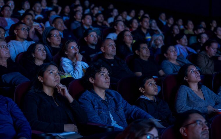 Espectadores observan una película de superhéroes en una sala de cine llena
