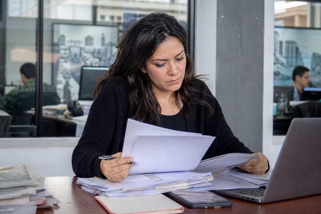 Periodista revisando documentos y fuentes digitales